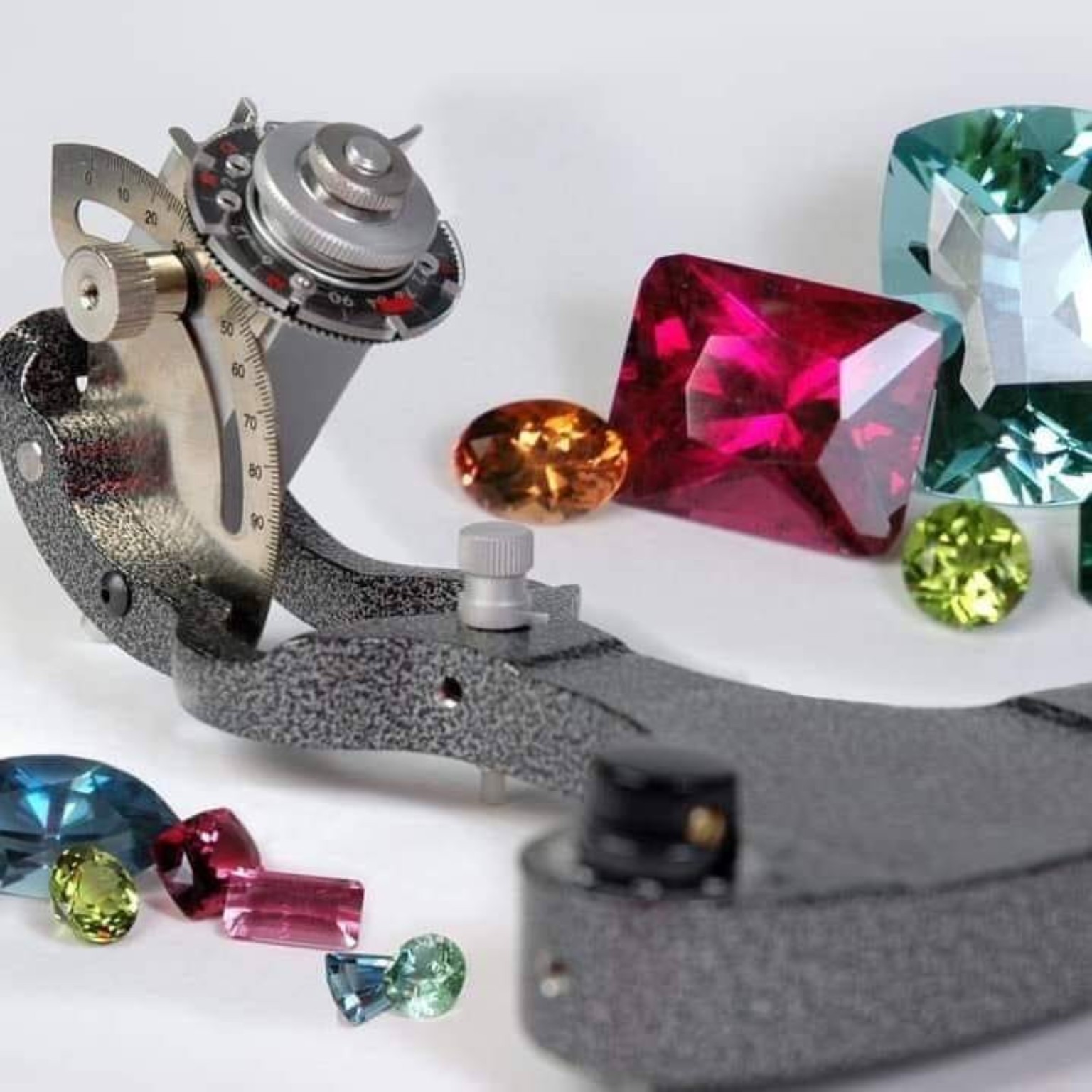 Faceting equipment beside colorful cut stones